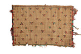 Vintage Tuareg straw mat with geometric triangle patterns in red, black, and teal.