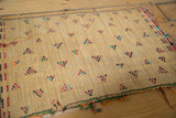 Intricate woven straw texture of a Tuareg mat with geometric motifs in red, black, and teal.