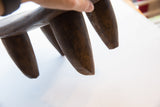 A low angle showing the three sturdy, hand-carved tapered legs of the Senufo wood stool.