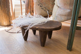 Detail of the vintage Senufo dark wood stool's hand-carved top with white foliage.