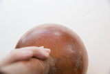 A hand holding the antique red slip ware vase, showing its scale and patina.