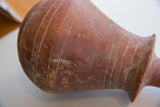 Incised horizontal lines and weathered surface patina on the antique red slip ware vase.