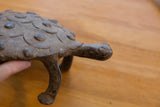 Textured concentric shell patterns and head of the vintage African turtle figure, held by a hand.