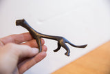 Slender vintage African cheetah sculpture with a dark patina held in hand for scale.