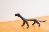 Profile view of a vintage African cheetah sculpture showing its handmade form and dark patina.