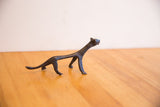 The elongated body and dark patina of the vintage African cheetah sculpture.