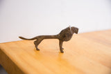 The aged, dark patina and handmade form of a vintage African lion sculpture in profile.