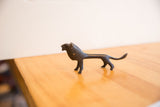 Handmade vintage African lion figurine with an elongated body and dark surface patina.