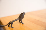The long, stylized body of a vintage African lion with a dark, textured patina.