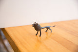 Side profile of the vintage African lion sculpture showing its slender body and dark patina.