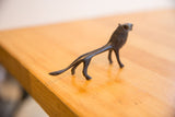 Angled view of the vintage lion's slender body and dark patina finish.