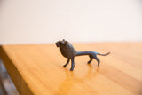 The slender profile of a handmade vintage African lion sculpture with a dark textured patina.