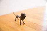 The dark, textured patina and handmade details on the face of a vintage African lion sculpture.