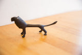The slender, elongated form and dark patina of the handmade African lion sculpture.