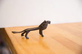 Full side profile of a vintage African lion, showing its elongated body and dark patina.