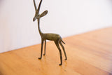The slender form and aged oxidized patina of a vintage gazelle figurine.