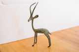 A vintage African gazelle figurine showing its slender form and oxidized patina.