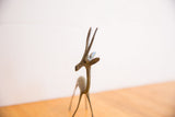 Aged patina and handmade texture on the head and horns of a vintage gazelle figure.