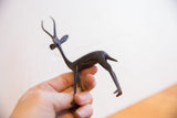 The handmade form and dark patina of a vintage gazelle sculpture held in hand.