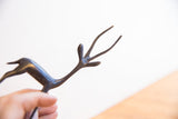 Close-up of the vintage gazelle sculpture's slender neck and stylized forked antlers.