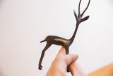 Hand holding the vintage gazelle sculpture, showing its small scale and dark patina.