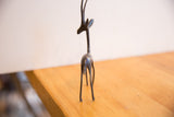Frontal view of a slender African gazelle sculpture with dark patina.