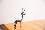 Vintage African gazelle sculpture showing its slender left-facing profile and aged dark patina.