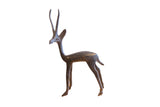 Vintage African gazelle sculpture facing left, with long horns and a dark aged patina.