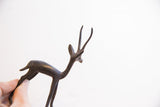 The slender form and dark patina of a vintage African gazelle held for scale.