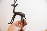 Vintage gazelle sculpture held in hand, showing its delicate size and dark handmade finish.