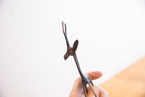 Detail of the dark, textured patina on the head and horns of a vintage gazelle sculpture.