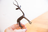 Vintage African gazelle sculpture held in hand to show its delicate scale and dark patina.