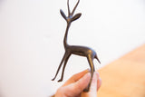 Small vintage African gazelle sculpture held to show its aged dark patina and scale.