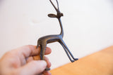A hand holds the vintage gazelle sculpture, highlighting its dark patina and handmade form.