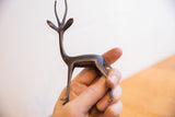 Hand holding the vintage African gazelle sculpture to show its small scale and dark patina.
