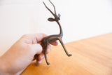 Vintage African gazelle sculpture held in a hand to show its scale and dark patina.