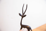 The stylized head and tall horns of a handmade African gazelle sculpture.