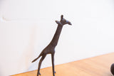 Side view of a vintage African giraffe showing its long neck and dark, textured patina.
