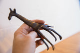 Hand holding the vintage African giraffe sculpture to highlight its handmade texture and dark patina.