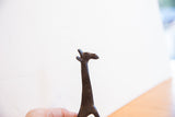 Profile view of the vintage giraffe sculpture's head, showing its dark, textured surface.