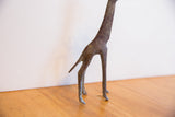 Side view of the vintage giraffe sculpture's slender legs and tail.