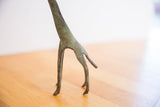 Close-up of the slender, hand-formed legs of the vintage giraffe sculpture showing its oxidized patina.
