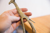Textured patina and handmade detail of a vintage giraffe sculpture held for scale.