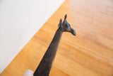 Angled view of a vintage African giraffe's sculpted head and dark patina.