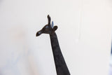 Profile view of the vintage giraffe head showing its dark patina and carved texture.