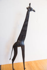 Profile view of the handmade African giraffe showing its dark patina and textured body.
