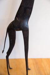 Close-up on the vintage giraffe's dark, textured body and sleek hind legs.