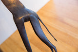 Close-up on the carved texture and dark patina of the vintage giraffe's hindquarters.