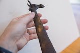 Hand holding the vintage African giraffe to show the dark, textured patina on its stylized head.