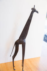 Full side view of the vintage African giraffe's slender form and dark, patterned patina.